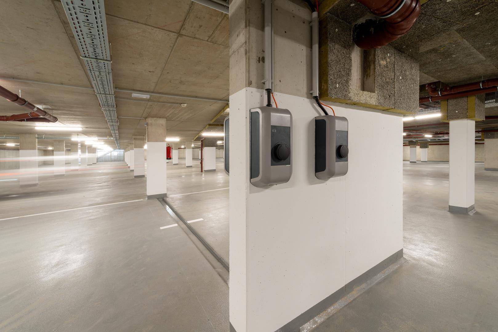 Moderne Tiefgarage mit Ladestationen für Elektrofahrzeuge an den Säulen.