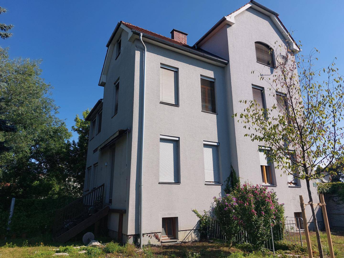 Nahaufnahme der Gebäudefassade mit Fenstern und geschlossenen Rollläden.