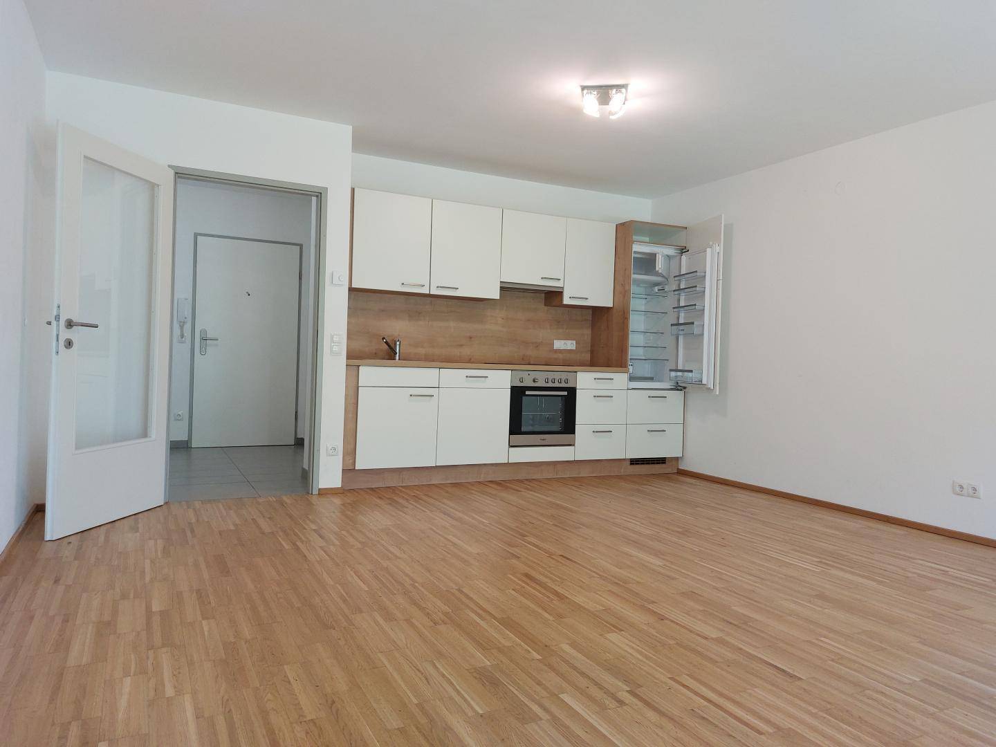 Heller Wohnbereich mit integrierter Küchenzeile und Holzboden.