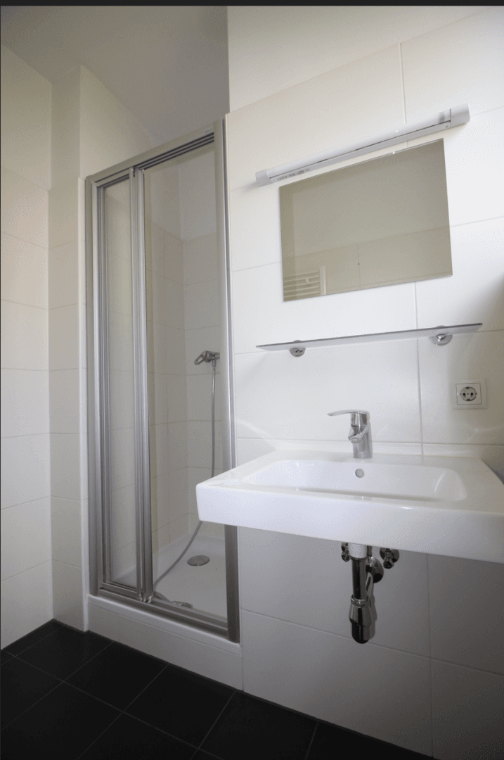 Helles Badezimmer mit Duschkabine, modernem Waschbecken und Wandspiegel.