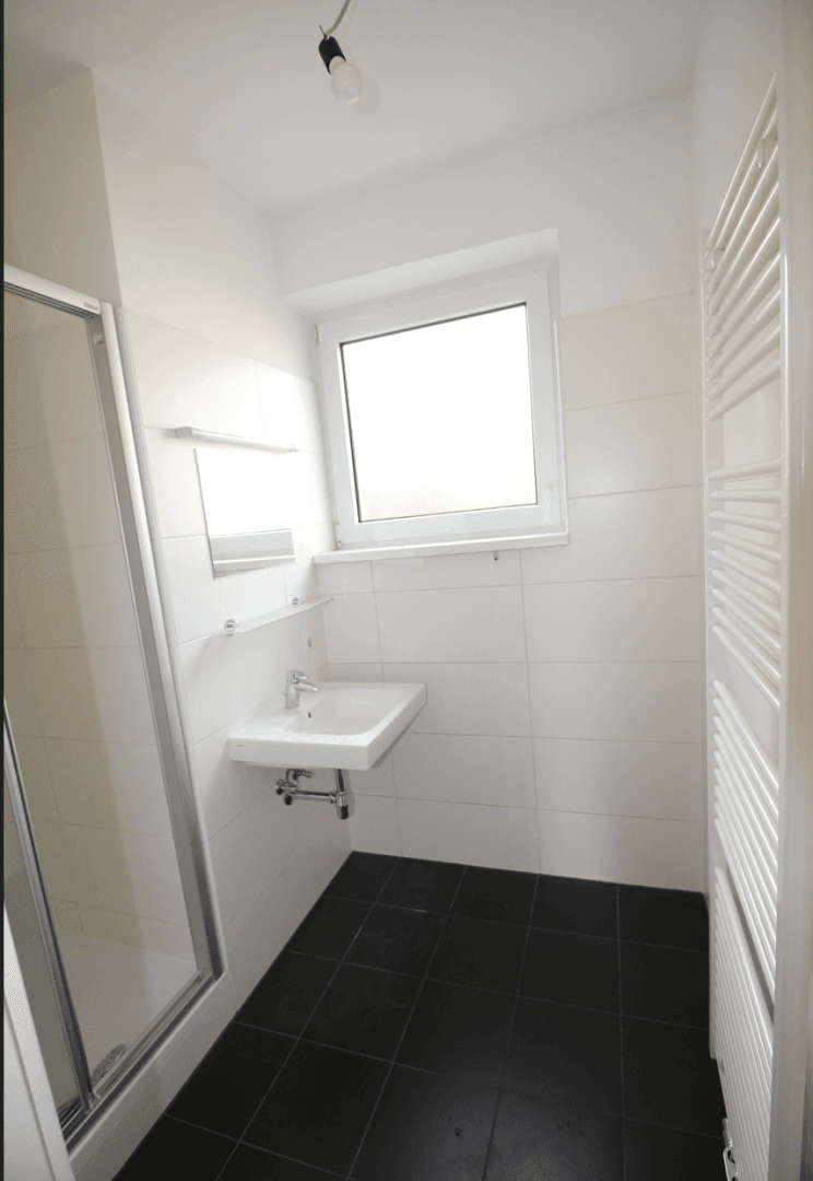 Modernes Badezimmer mit Dusche, Waschbecken, Fenster und beheiztem Handtuchhalter.