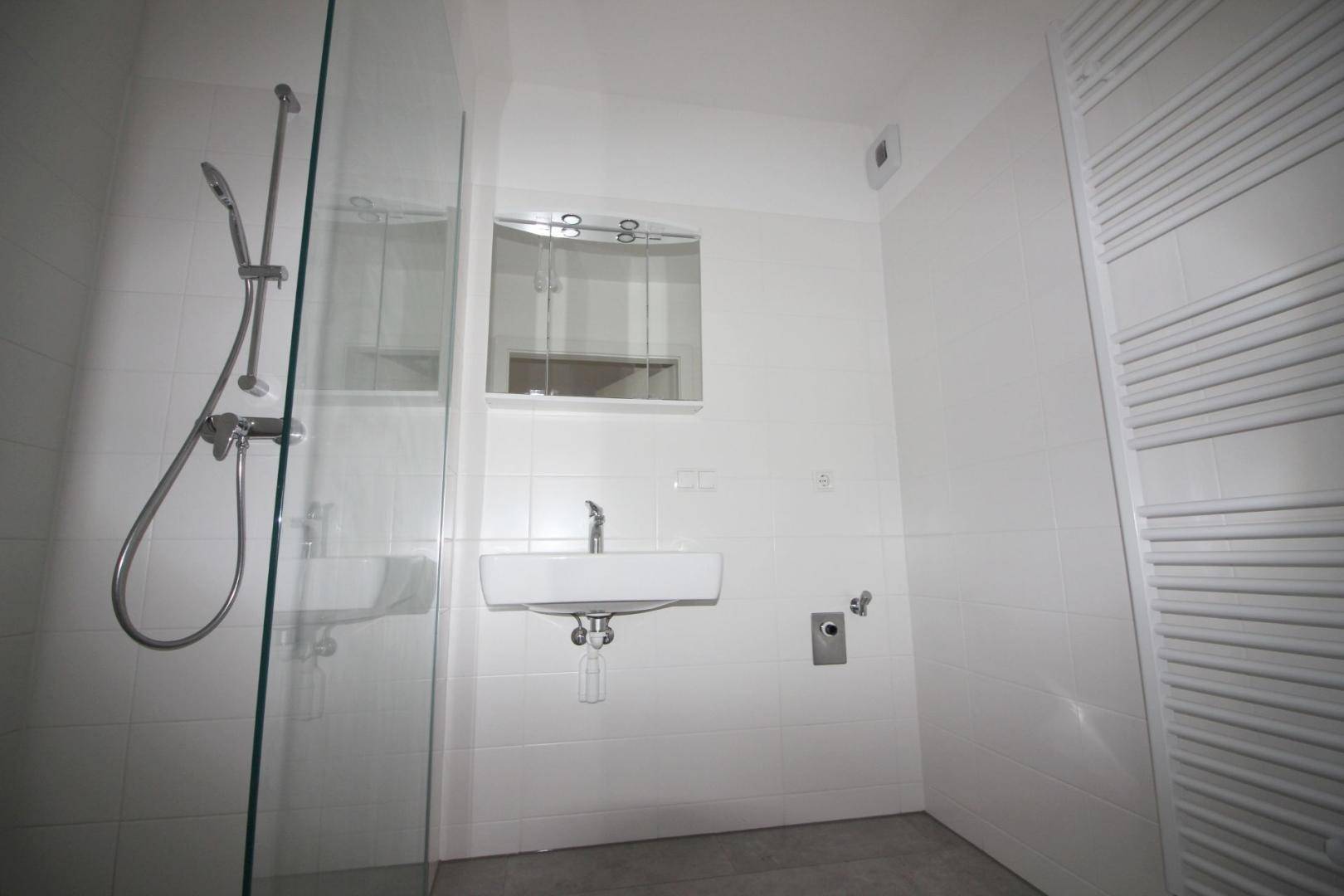 Modernes Badezimmer mit Dusche, Waschbecken und beheiztem Handtuchhalter.