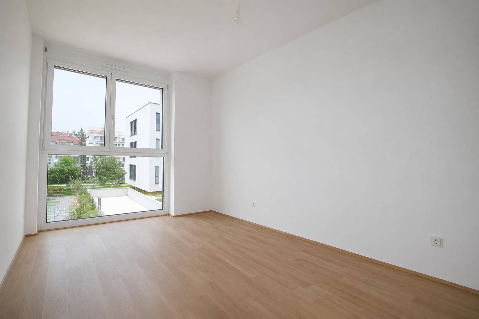 Helles Schlafzimmer mit großen Fenstern und Blick auf den Innenhof.