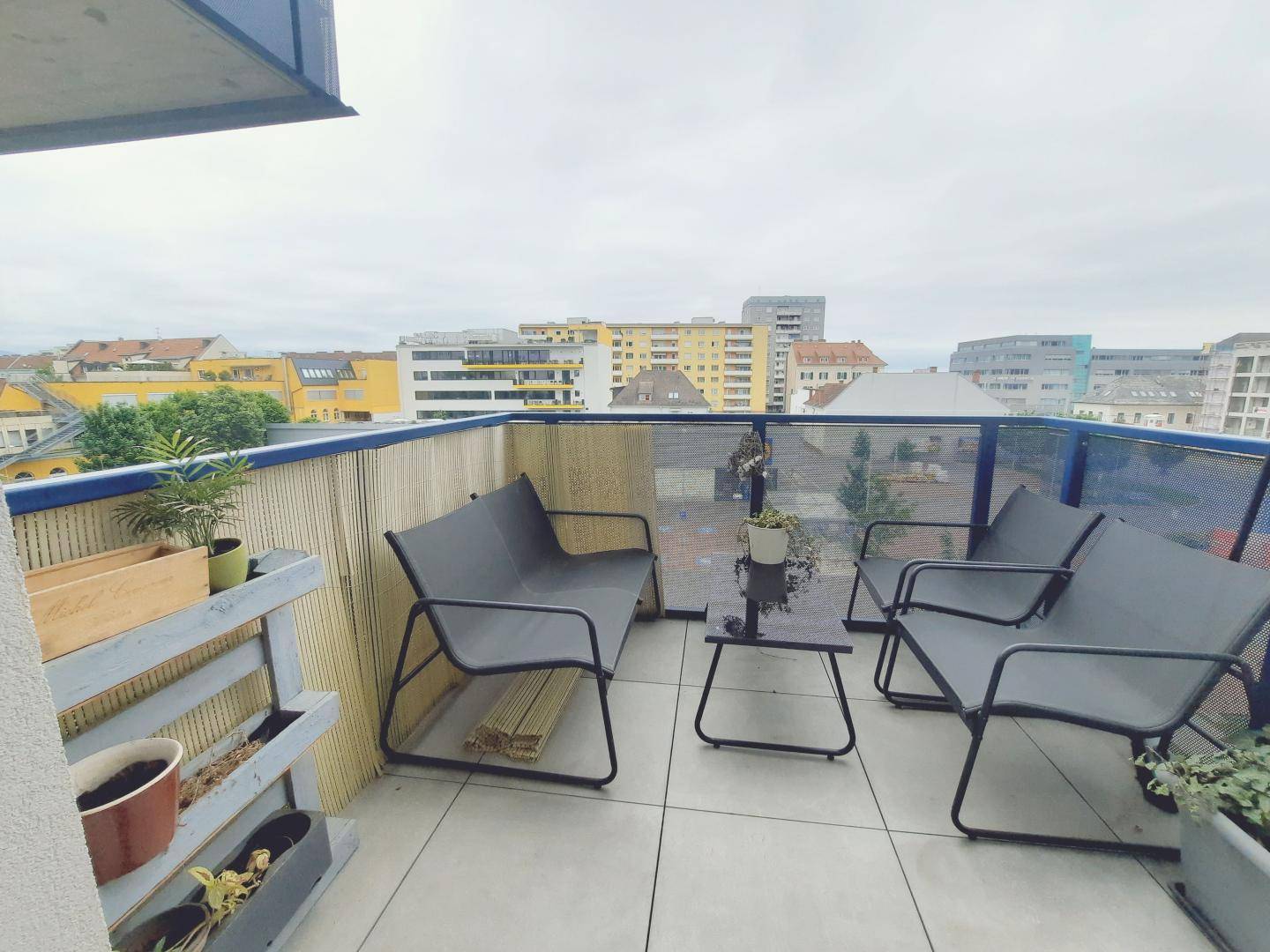 Möblierter Balkon mit Fliesenboden und Blick auf die umliegende Stadtbebauung.