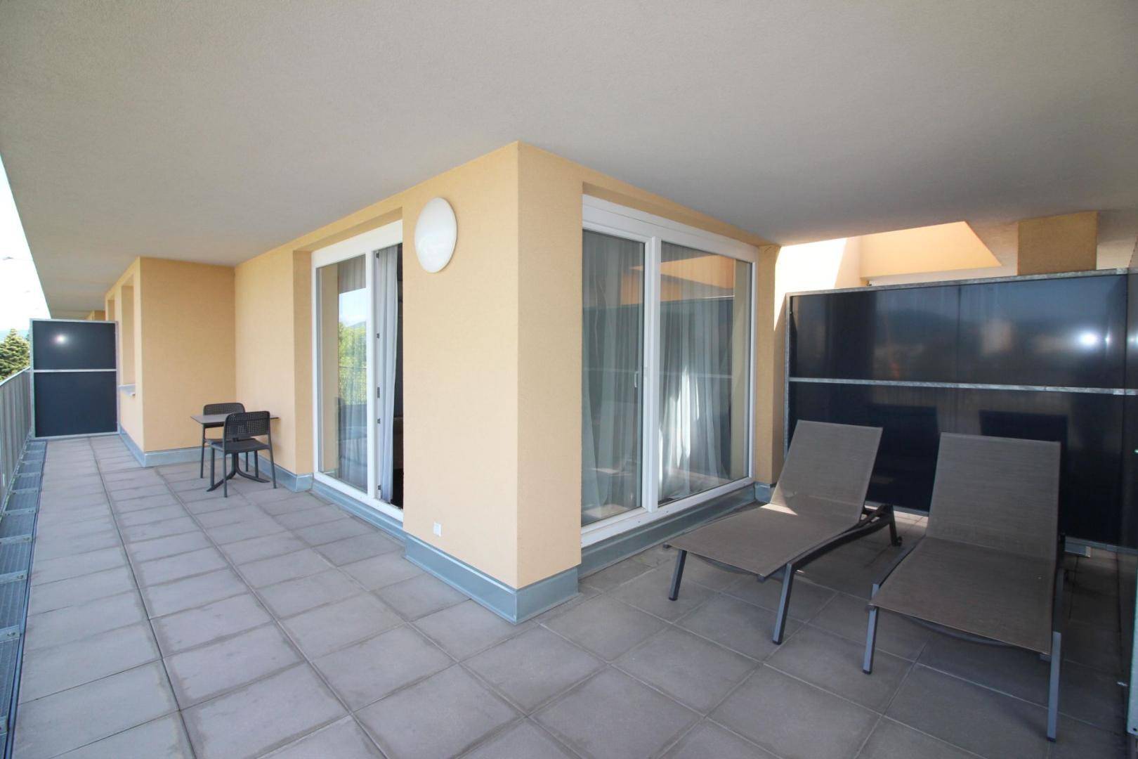 Geräumige Terrasse mit Fliesenboden, Sonnenliegen und Sitzgelegenheiten für entspannte Stunden.
