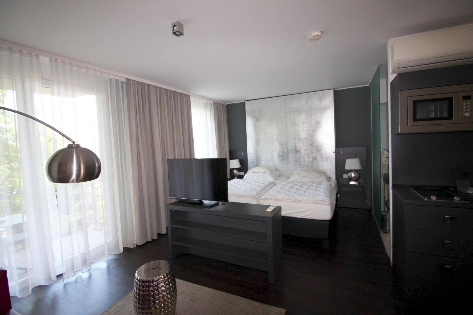 Helles Studio-Apartment mit großem Fenster, Doppelbett und modernem Interieur.