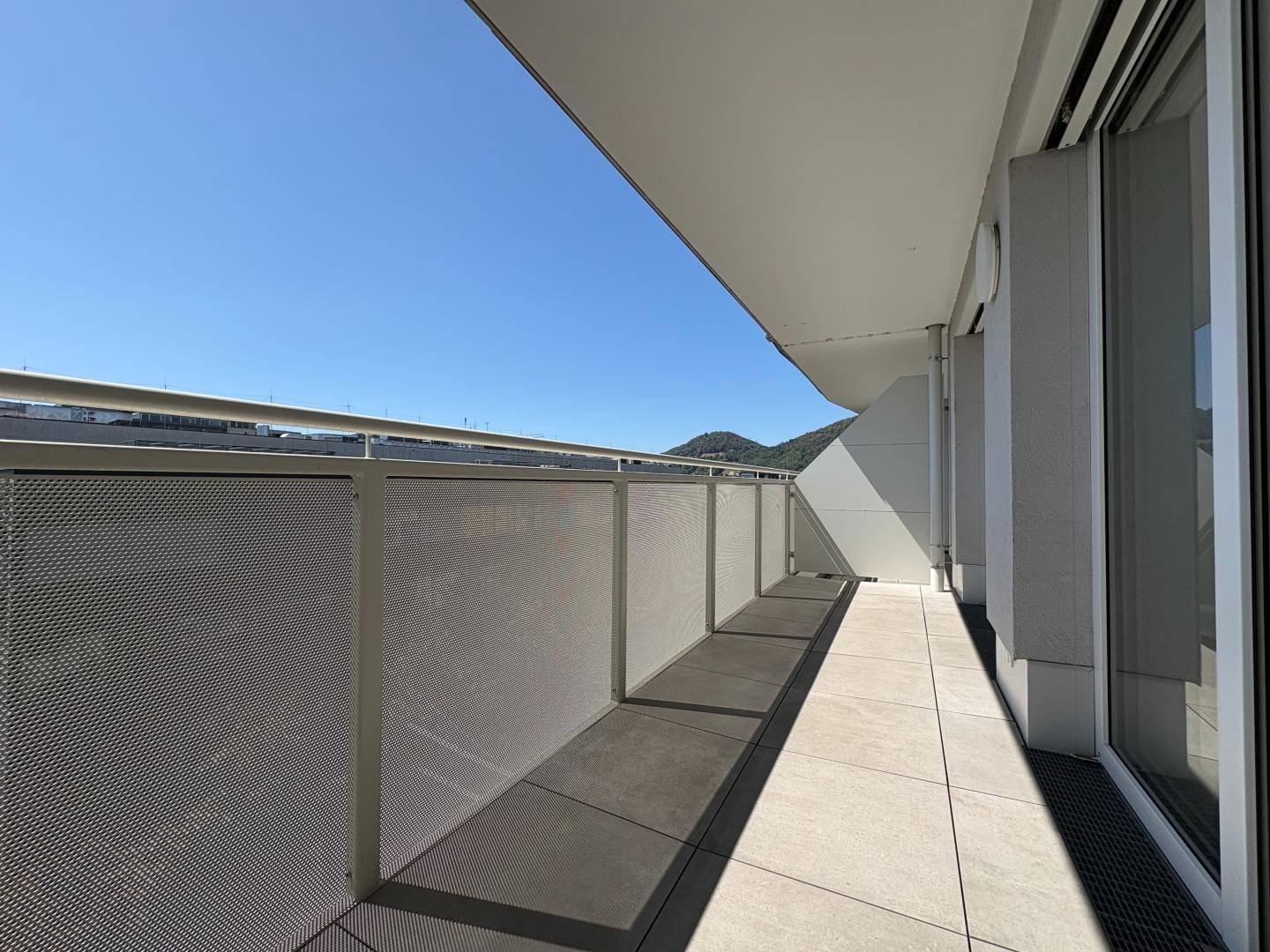Langer, schmaler Balkon mit modernem Metallgeländer und Fliesenboden, ideal für entspannte Stunden.