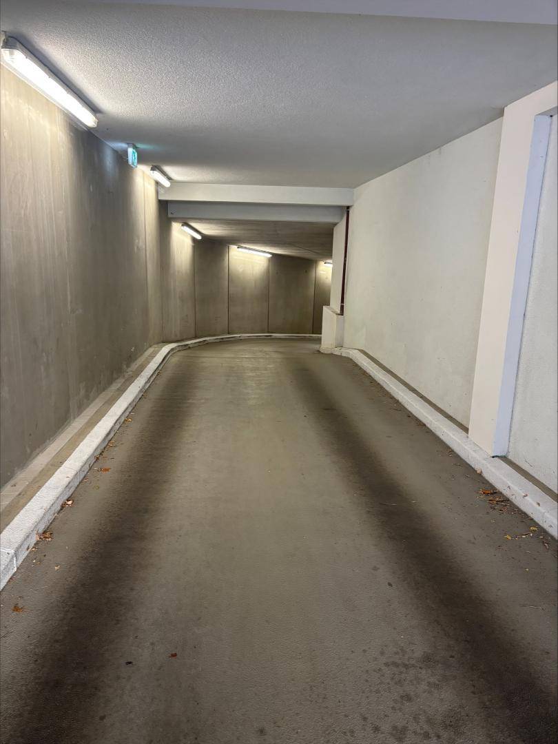 Einfahrt zur Tiefgarage mit Betonwänden und Beleuchtung.