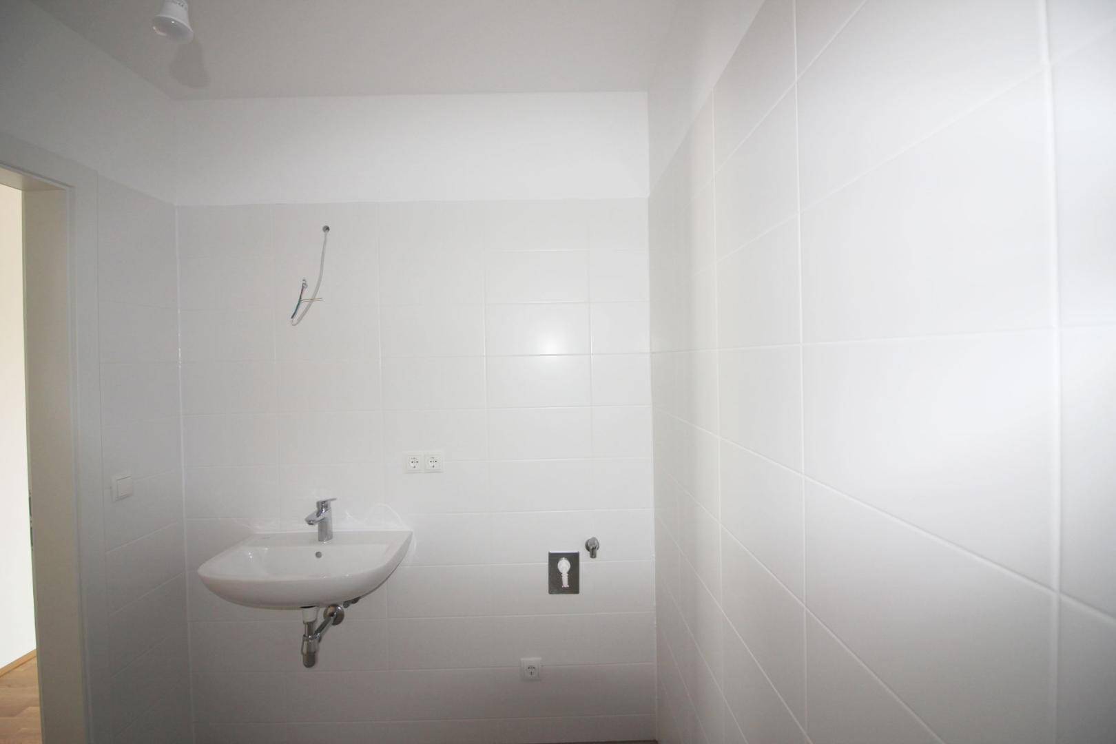 Modern gefliestes Badezimmer mit Waschbecken und weißen Wandfliesen.
