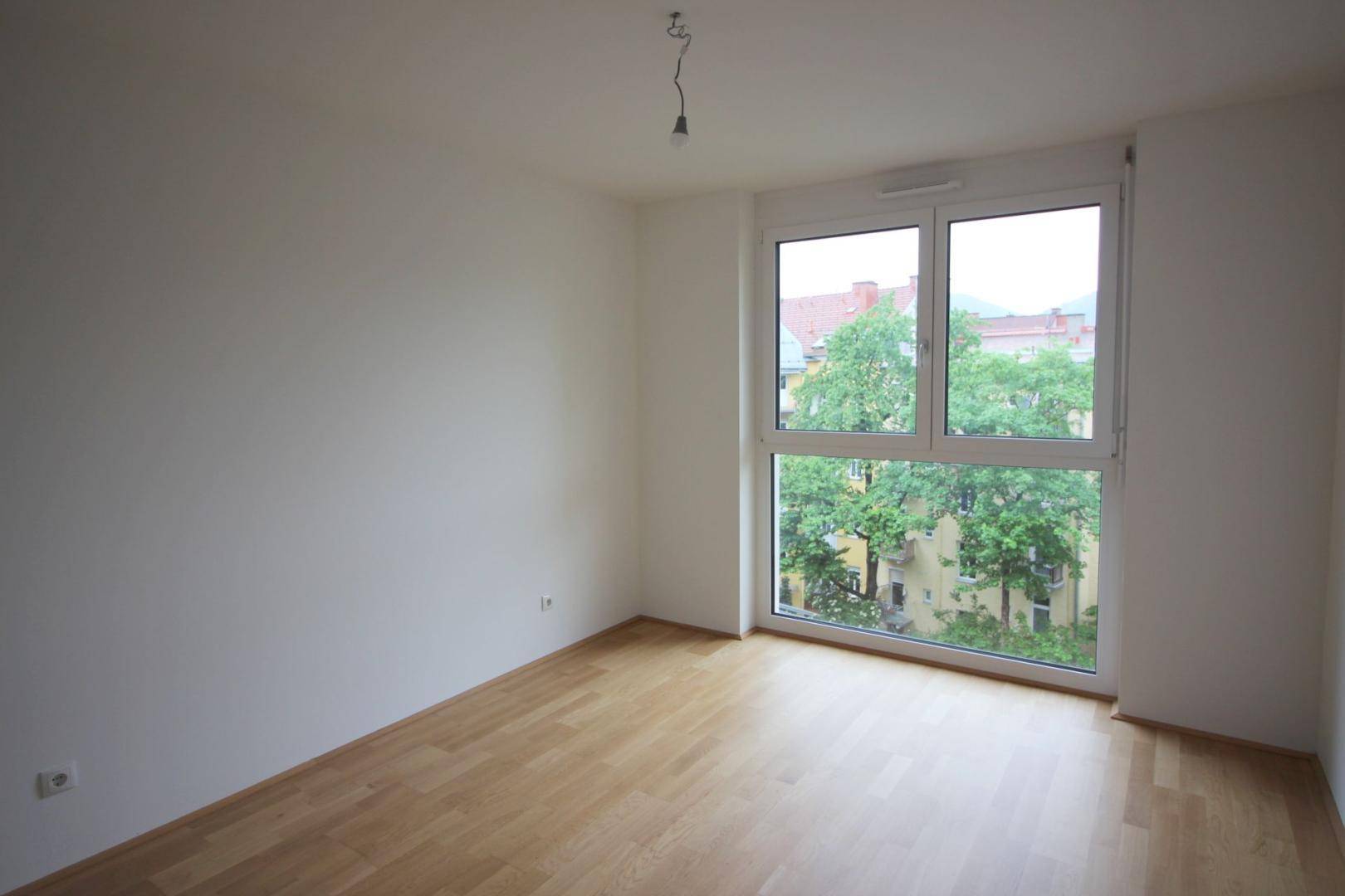 Schlafzimmer mit großen Fenstern, die viel Tageslicht hereinlassen und einen grünen Ausblick bieten.