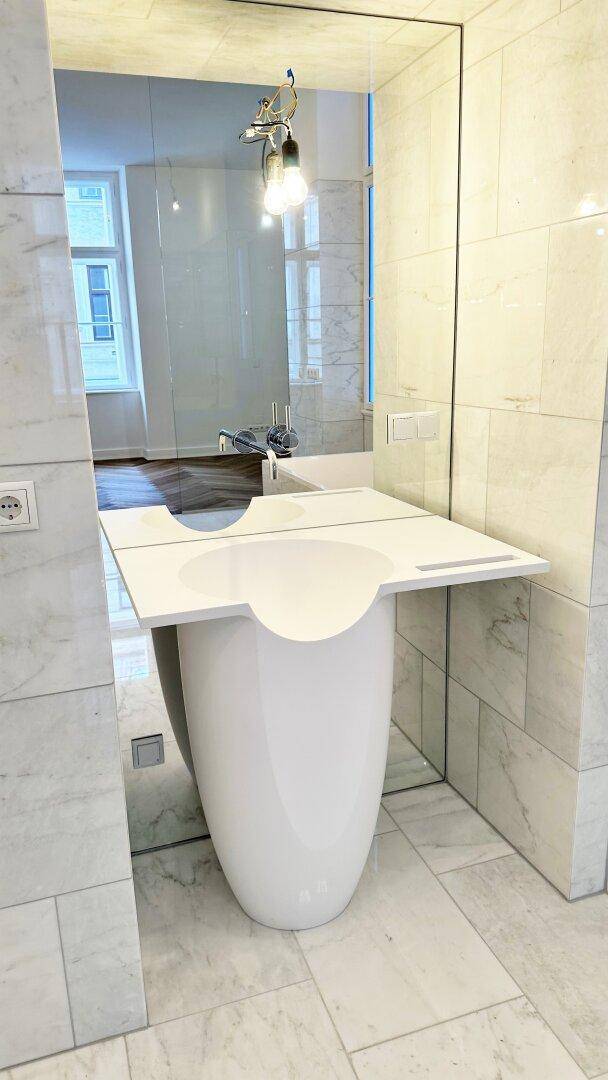 Moderner Waschtisch mit einzigartigem Design und großem Spiegel in einem Marmorbad.
