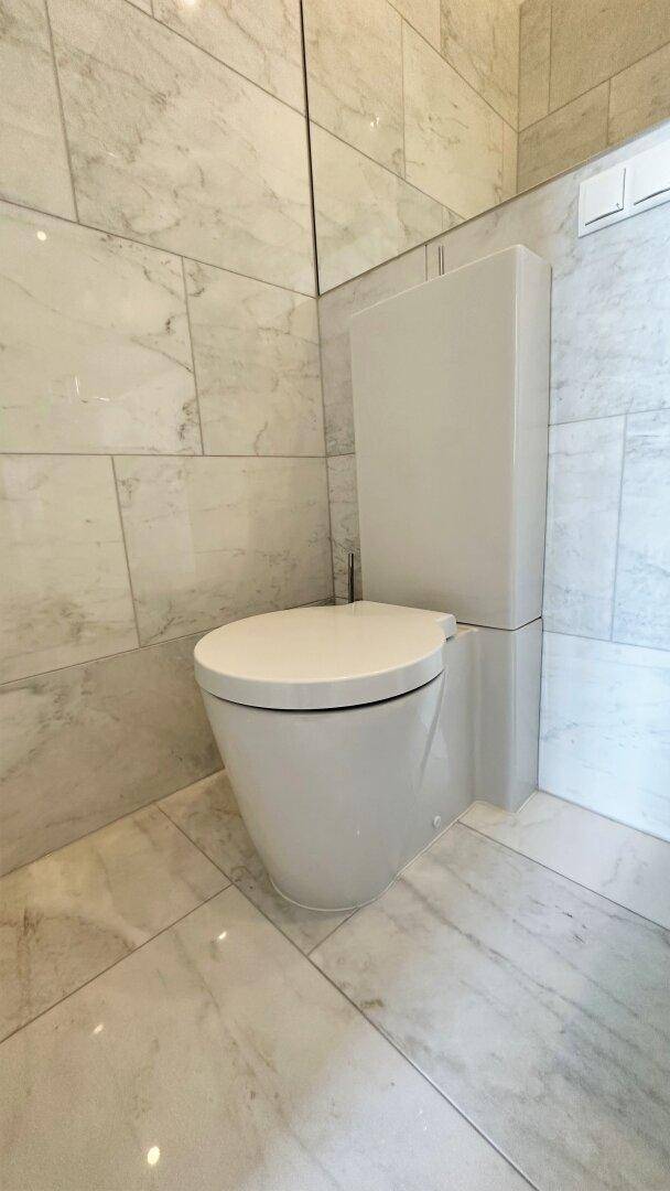 Nahaufnahme einer modernen, wandhängenden Toilette in einem elegant gefliesten Badezimmer.