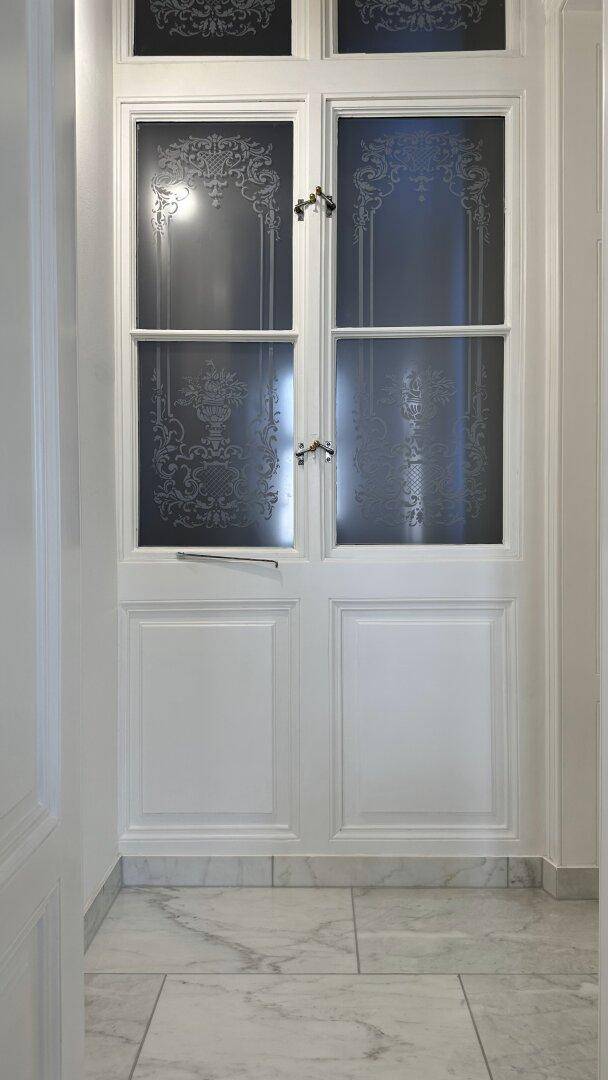 Detailaufnahme einer eleganten Doppeltür mit satiniertem Glas und dekorativen Mustern.