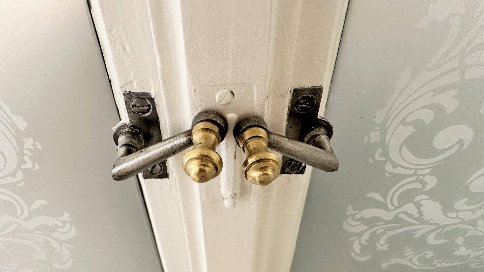 Detailaufnahme von klassischen Fenstergriffen mit goldfarbenen Akzenten.