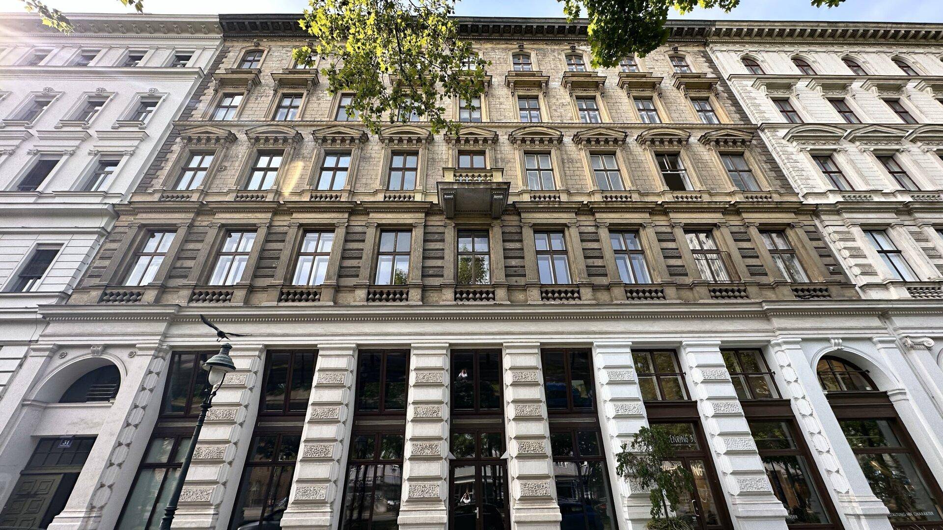 Historische Fassade eines Stadthauses mit vielen Fenstern und einem kleinen Balkon.