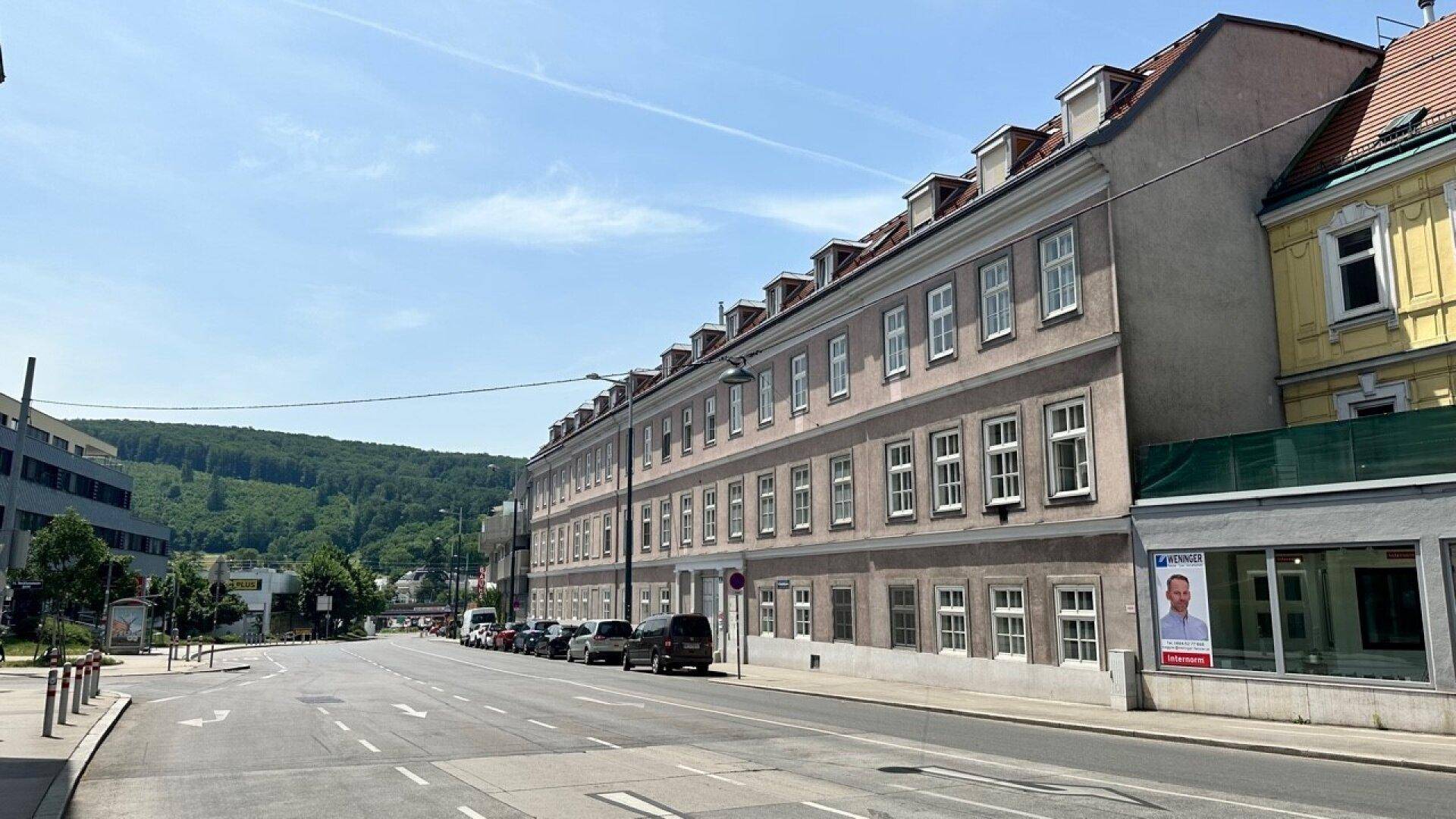 Historisches Gebäude mit vielen Fenstern entlang einer belebten Straße an einem sonnigen Tag.