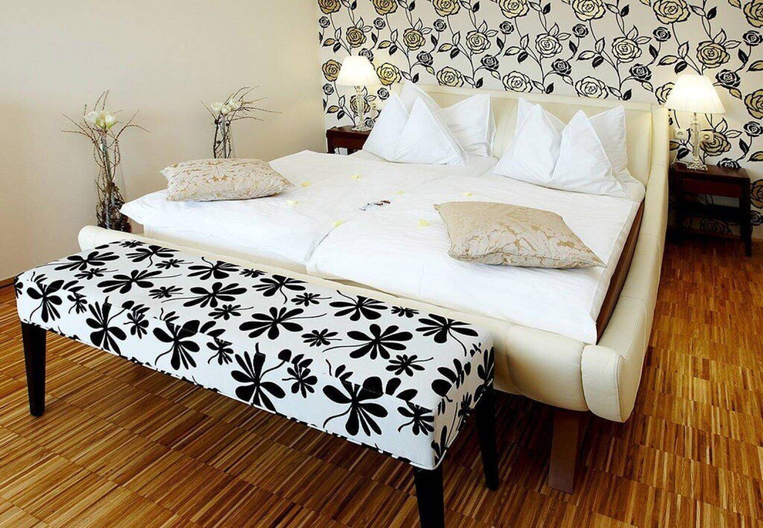 Gemütliches Schlafzimmer mit Doppelbett, Holzboden und einer auffälligen floralen Tapete.