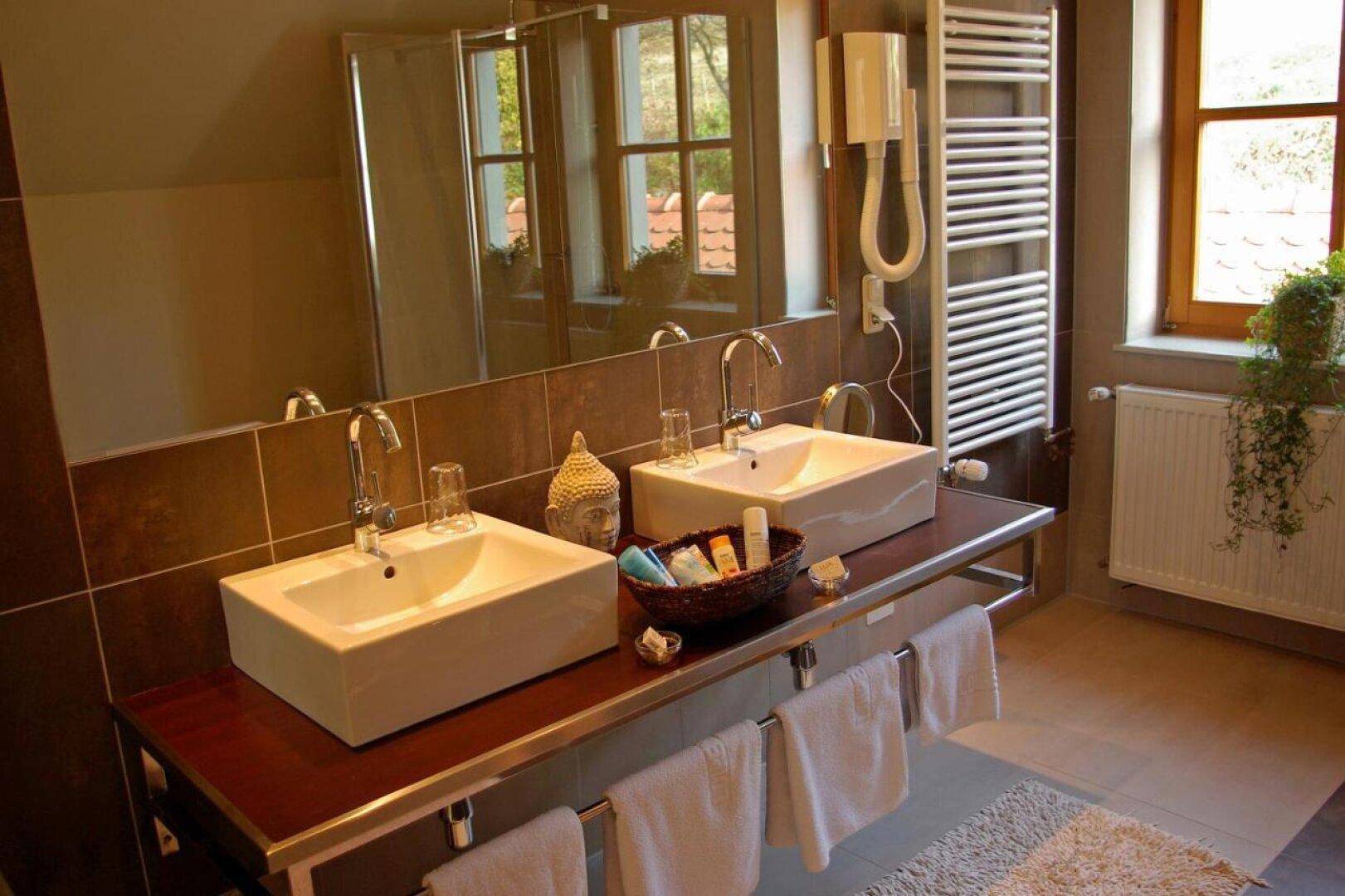 Modernes Badezimmer mit Doppelwaschbecken, großer Spiegelfläche und einer Duschkabine.