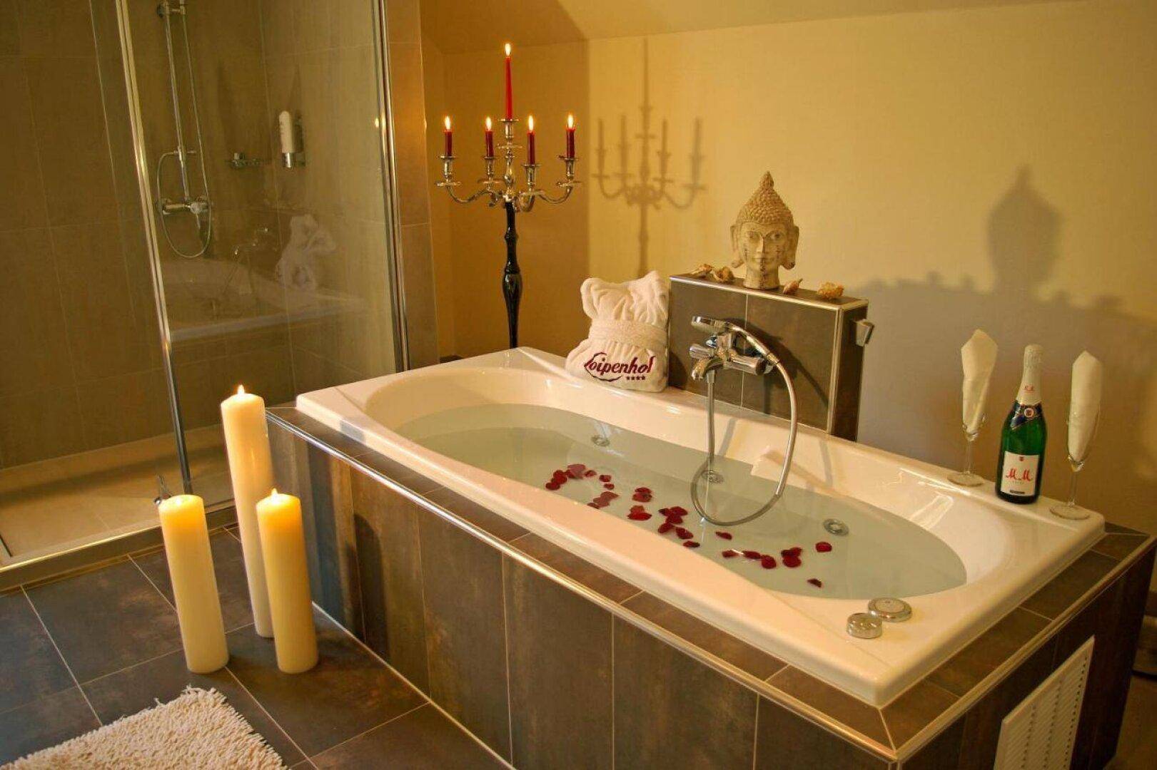 Entspannendes Badezimmer mit Badewanne, Duschbereich und stimmungsvoller Kerzenbeleuchtung.