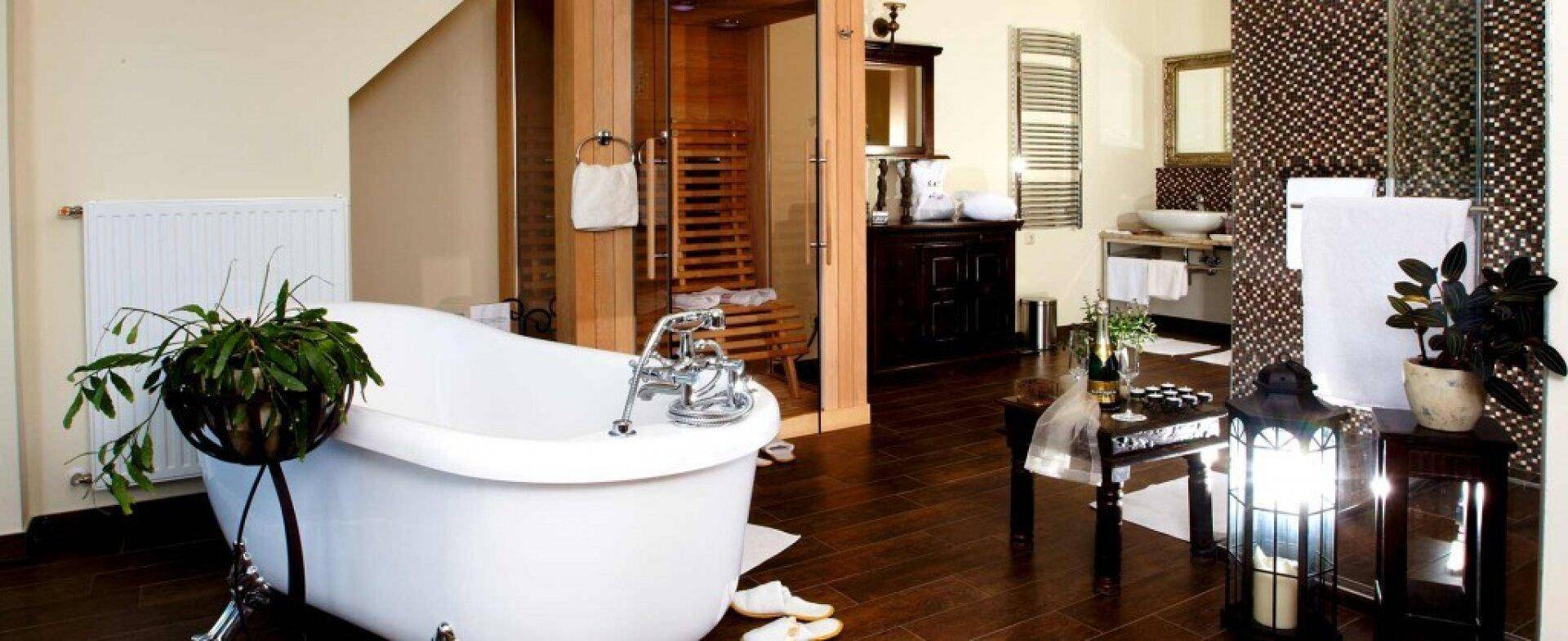 Großzügiges Badezimmer mit freistehender Badewanne, Sauna und dunklem Holzboden.
