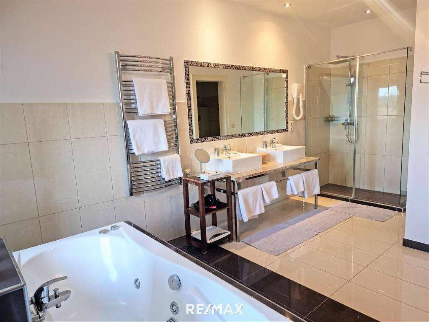 Geräumiges Badezimmer mit Whirlpool-Badewanne, Doppelwaschbecken und großer Duschkabine.