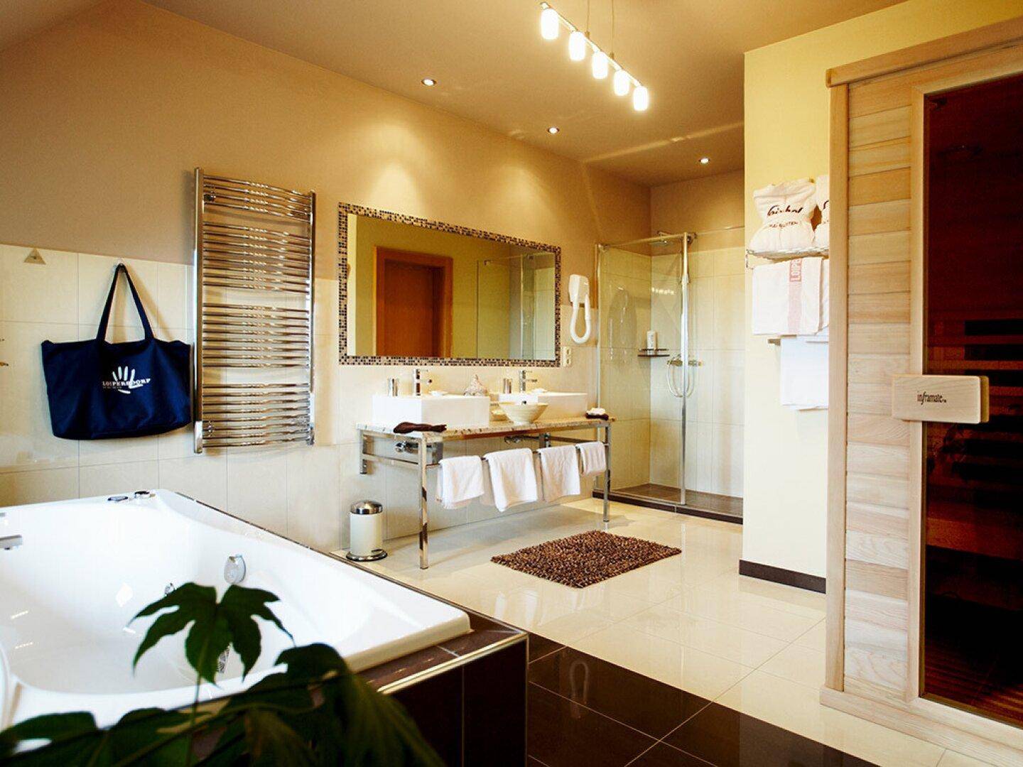Helles Badezimmer mit Whirlpool, Sauna, Doppelwaschbecken und Handtuchheizkörper.