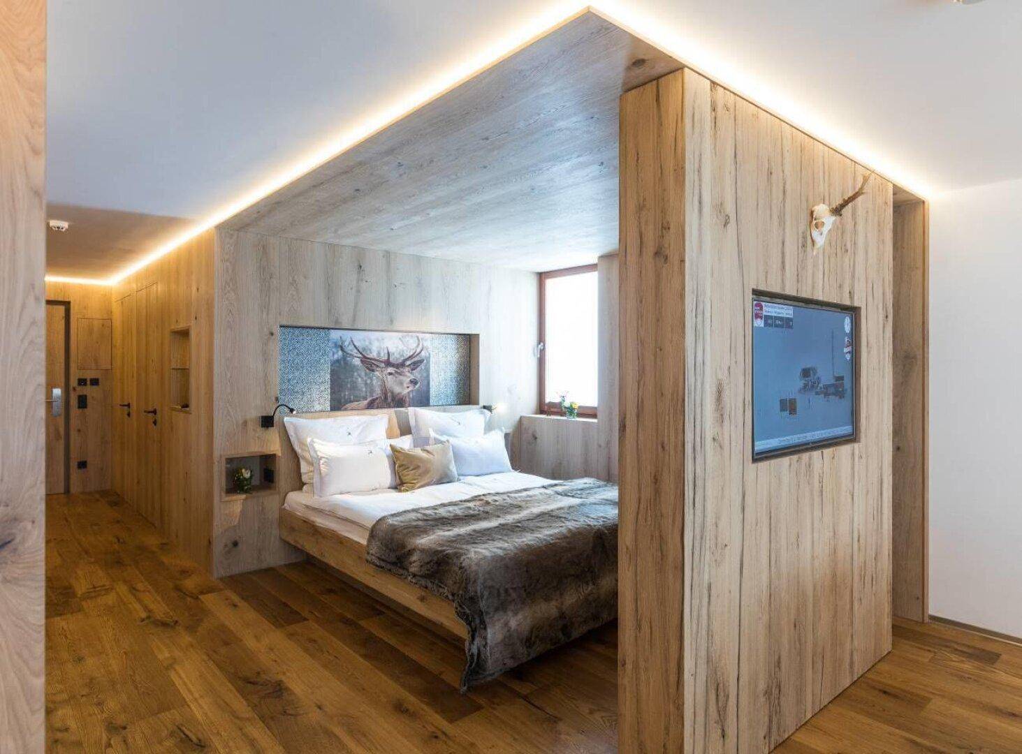 Schlafzimmer im alpinen Stil mit Holzelementen, integriertem Bett und indirekter Beleuchtung.