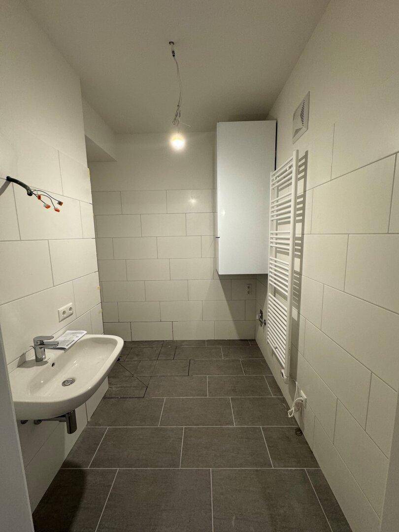 Modernes Badezimmer mit Fliesenboden, Waschbecken und beheiztem Handtuchhalter.