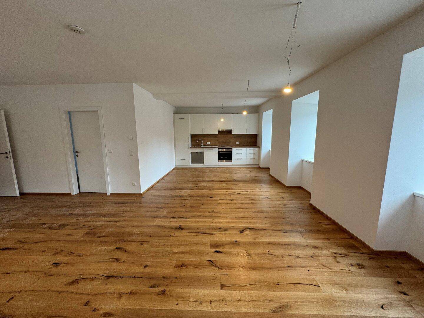 Offener Wohnbereich mit integrierter Küche, Holzdielenboden und viel natürlichem Licht.
