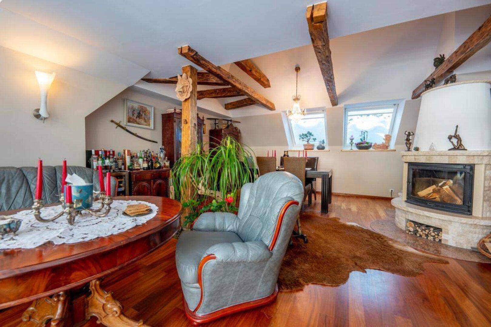 Gemütlicher Wohn-Essbereich mit Holzbalken, Kamin und traditionellen Möbeln, ideal für gesellige Abende.