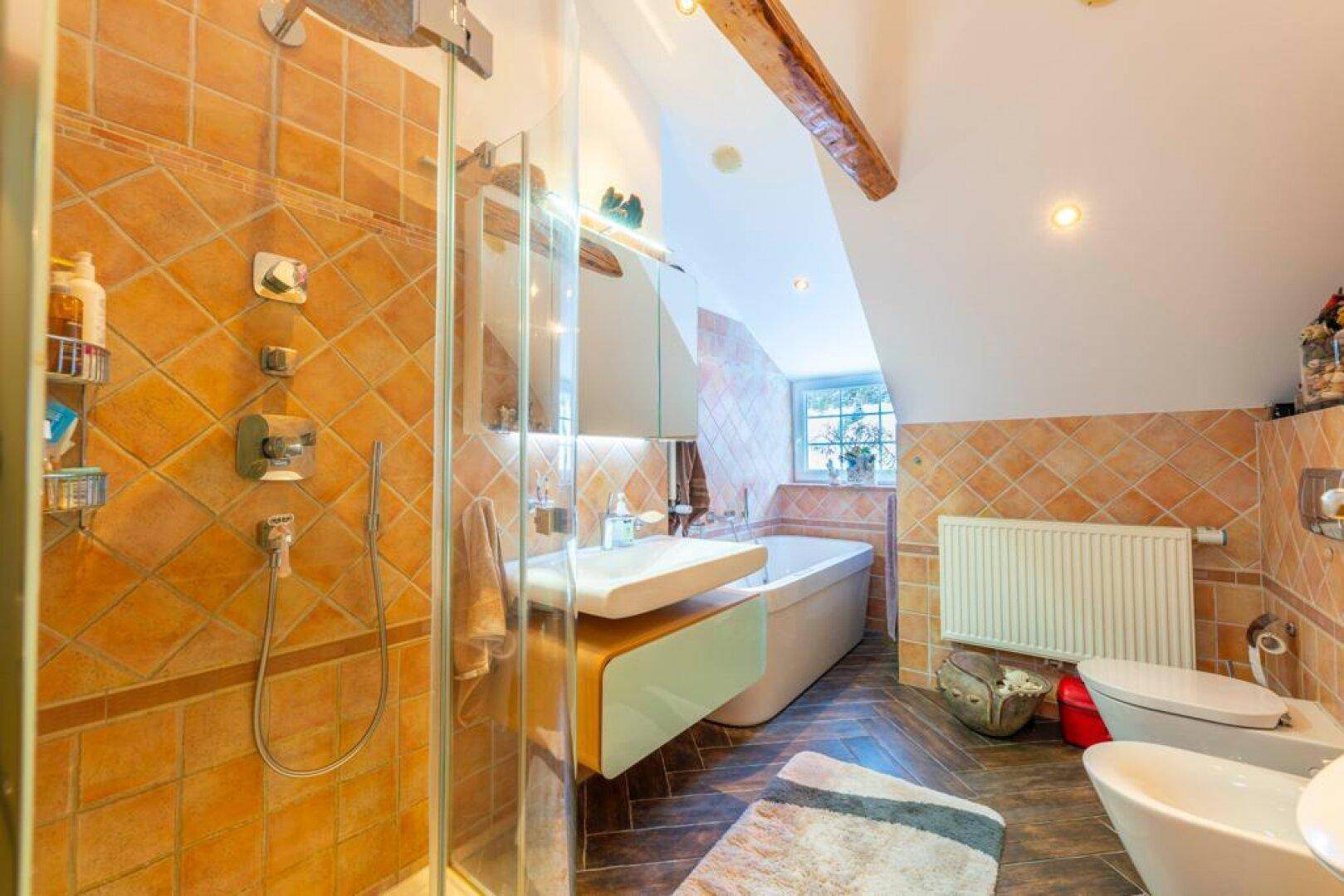 Modernes Badezimmer mit terracottafarbenen Fliesen, Duschkabine, Badewanne und Dachschräge.