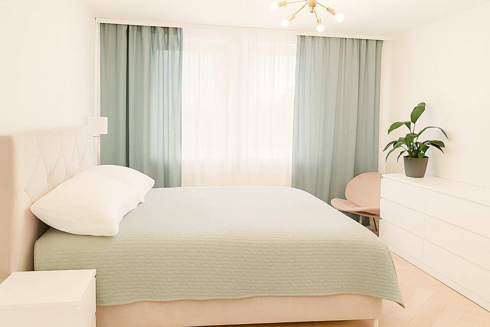 Gemütliches Schlafzimmer mit Doppelbett, hellen Vorhängen und einem Nachttisch.