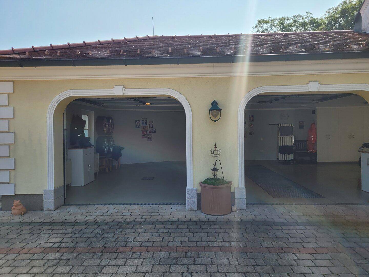 Doppelgarage mit geöffneten Toren und gepflasterter Zufahrt.