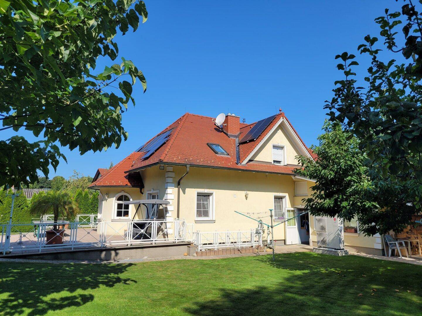 Rückansicht des Hauses mit Garten, Rasenfläche und Solaranlage auf dem Dach.