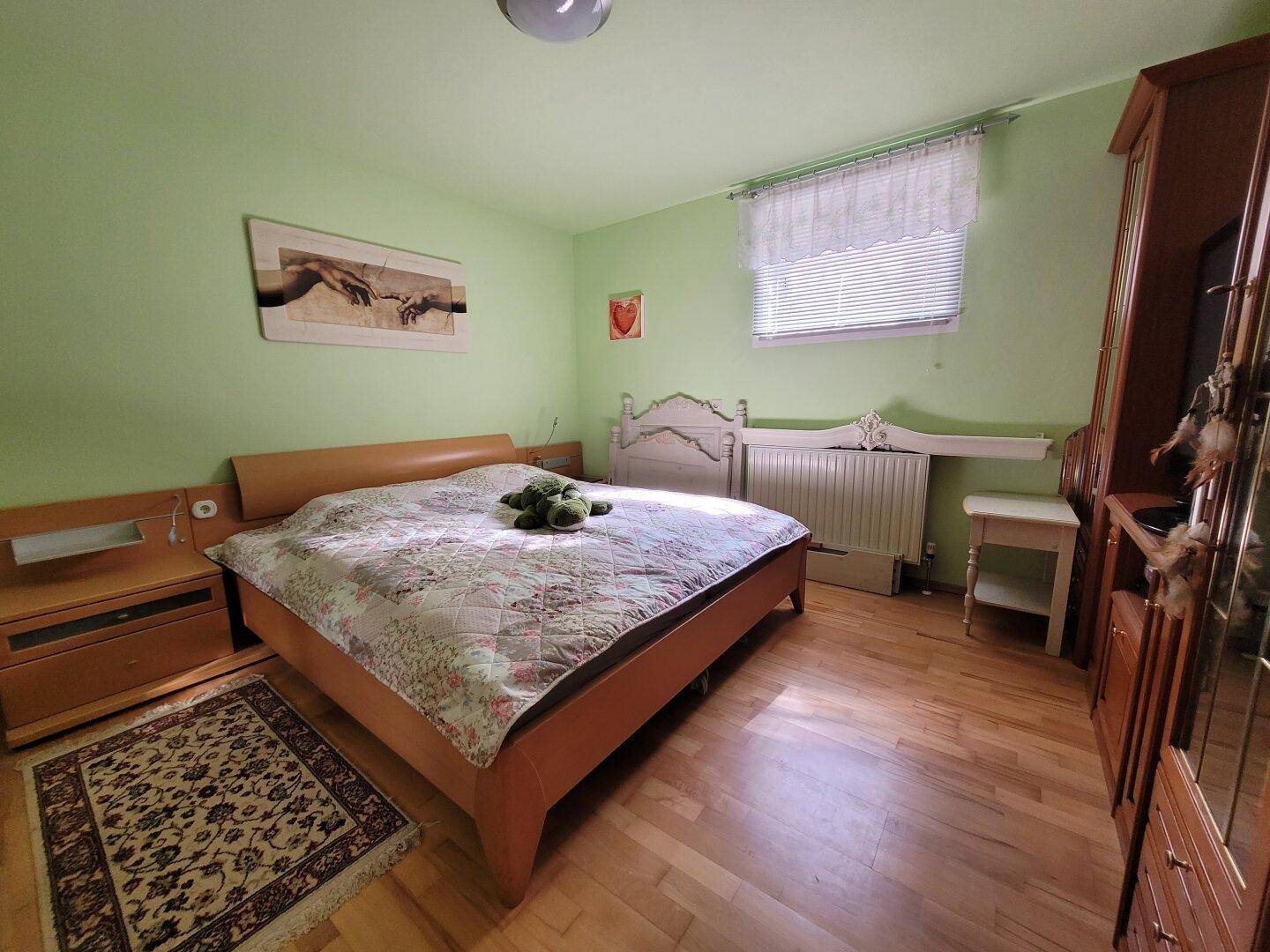 Geräumiges Schlafzimmer mit grün gestrichenen Wänden, Holzboden und Doppelbett.