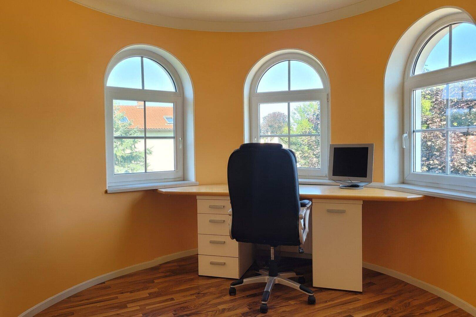 Arbeitszimmer im Turmzimmer mit Rundbogenfenstern und Blick ins Grüne.