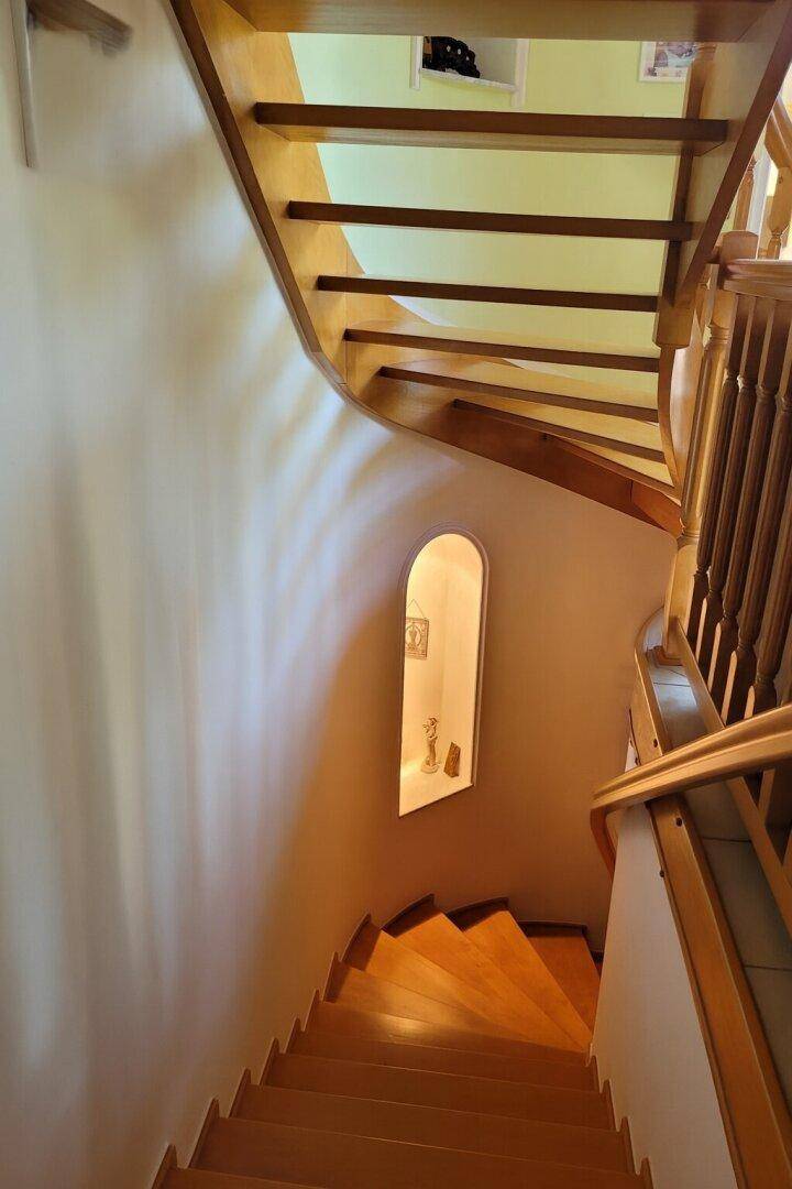 Geschwungene Holztreppe mit Nische und indirekter Beleuchtung.