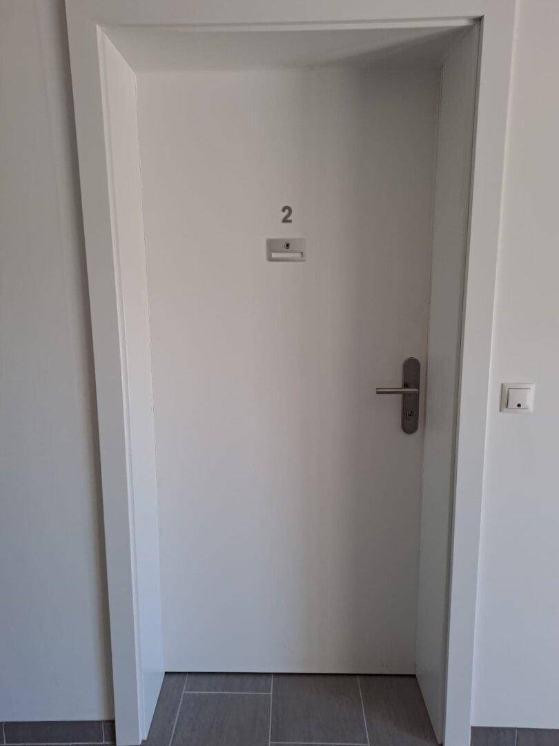 Eingangstür einer Wohnung mit Nummer zwei in einem modernen Flurbereich mit Fliesenboden.