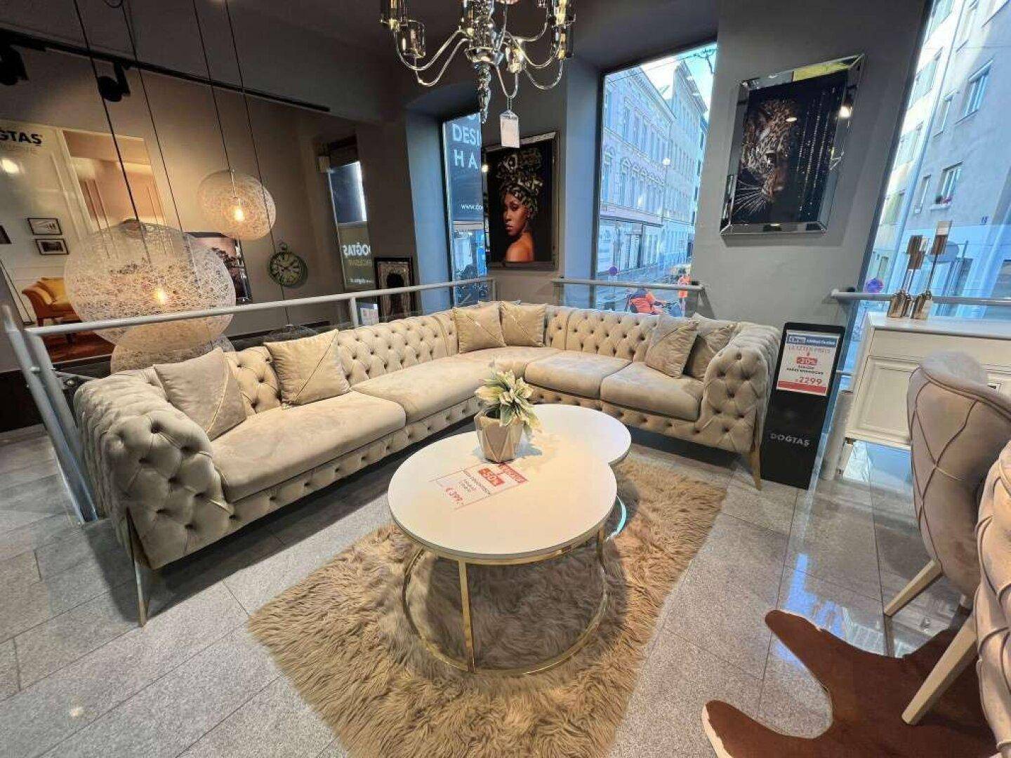 Eleganter Wohnbereich mit einem großen, getufteten Ecksofa und runden Couchtischen auf einem flauschigen Teppich.