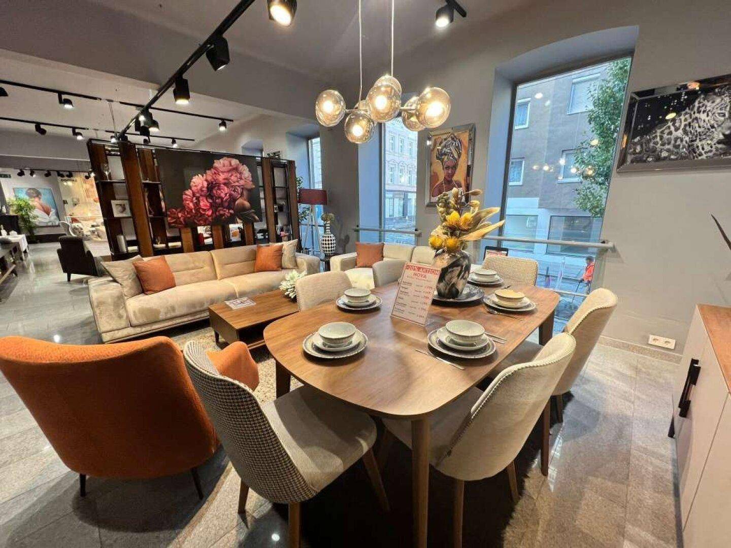 Stilvoller Essbereich mit Holztisch, modernen Stühlen und einem Kronleuchter, umgeben von Wohnmöbeln.