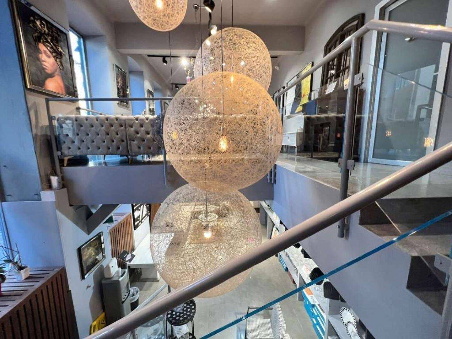Treppenhausbereich mit großen, dekorativen Hängelampen und Blick auf weitere Ausstellungsflächen.
