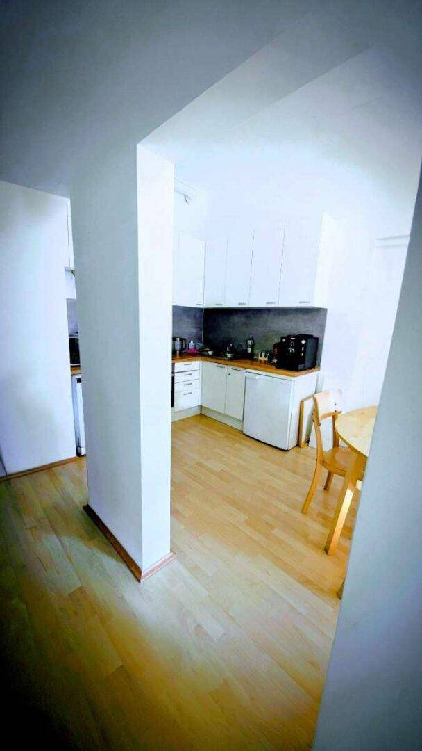 Kleine, funktionale Küchenzeile mit weißen Schränken und Holzboden, ideal für eine schnelle Mahlzeit.
