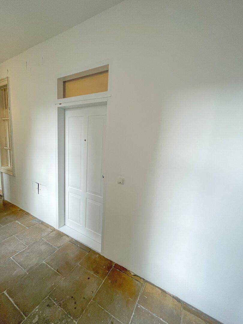 Heller Flur mit Steinboden und einer eleganten Eingangstür, die den Zugang zum Gebäude ermöglicht.