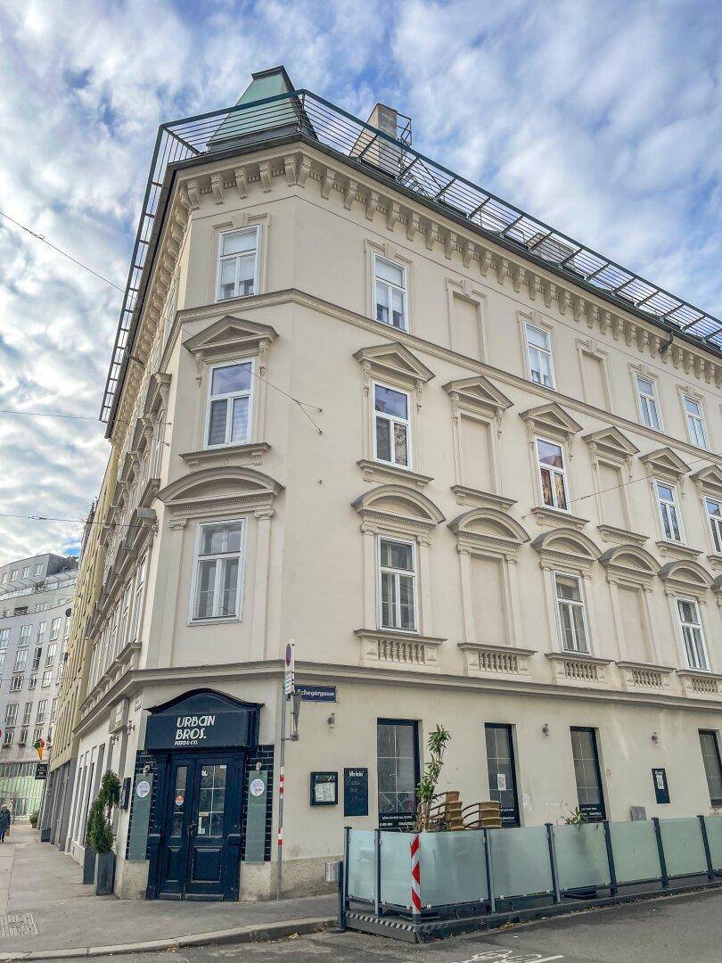 Historisches Eckgebäude mit klassischer Fassade und Geschäften im Erdgeschoss, an einer städtischen Straße gelegen.
