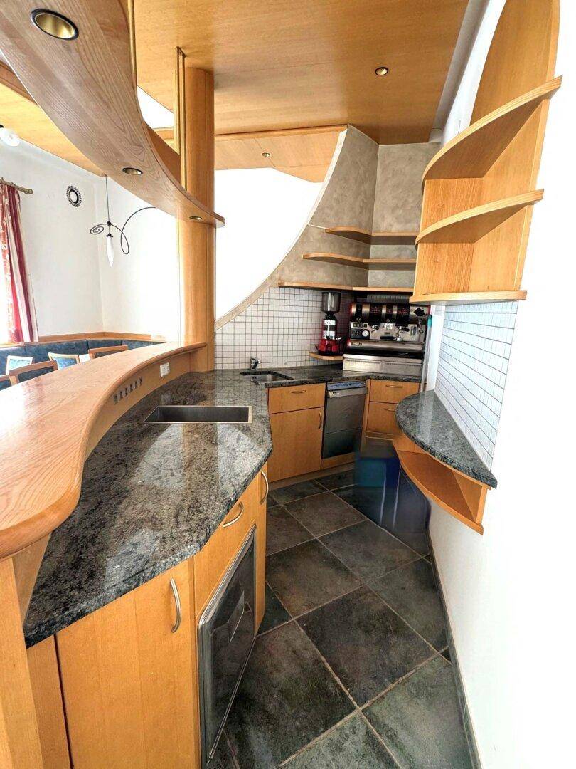 Eine moderne Küche mit geschwungenen Holztheken, Granitarbeitsplatten und dunklen Fliesenböden.