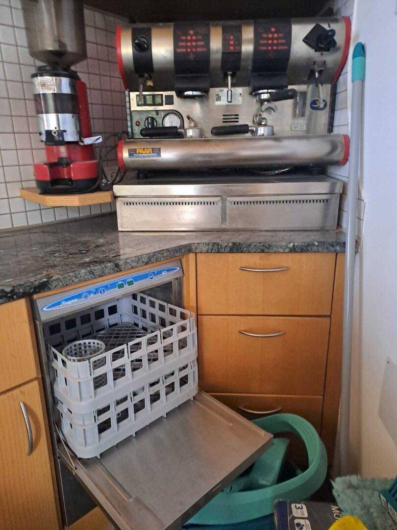 Professionelle Kaffeemaschine und integrierter Geschirrspüler in einer Küche mit Granitarbeitsplatte.