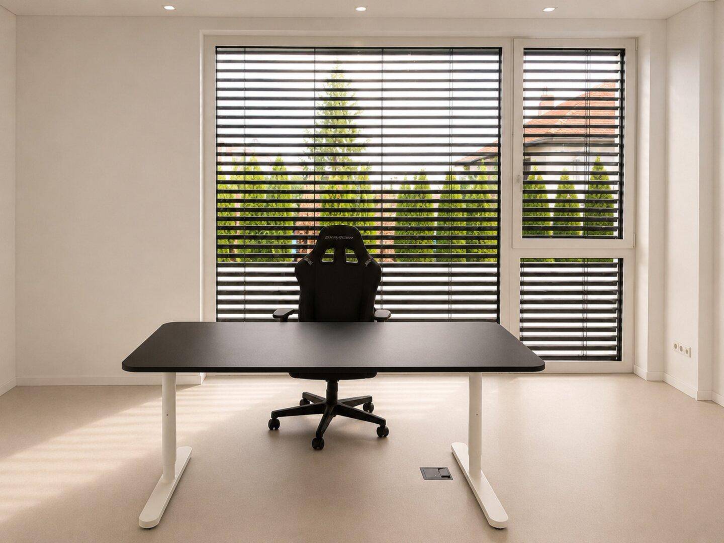 Helles Arbeitszimmer mit großem Fenster, modernem Schreibtisch und Blick ins Grüne.