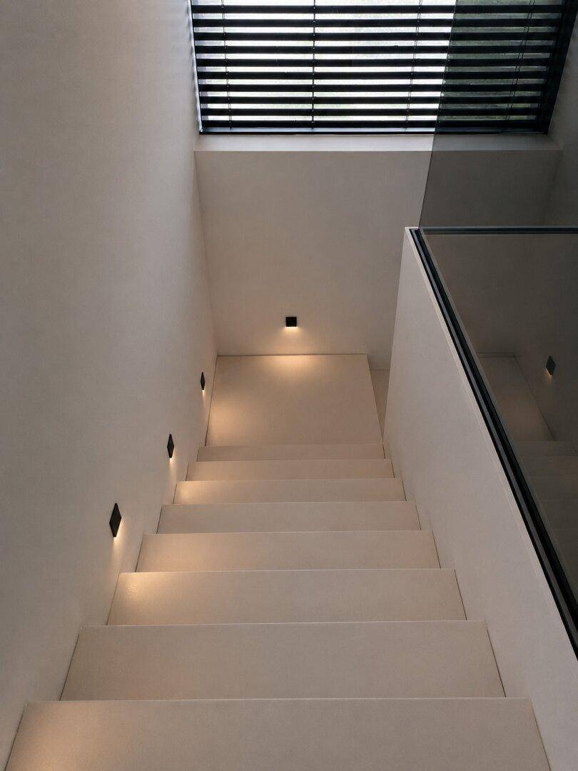 Moderne Treppe mit minimalistischem Design, Glasgeländer und integrierter Beleuchtung für eine stilvolle Atmosphäre.