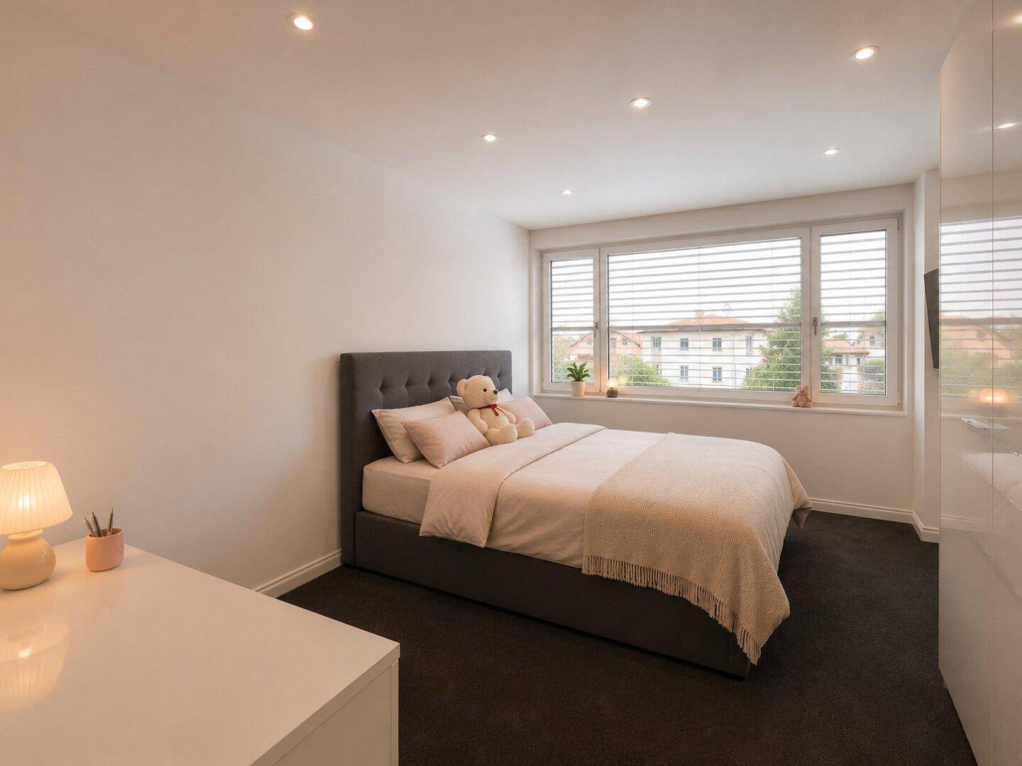 Gemütliches Schlafzimmer mit Doppelbett, Teppichboden und großem Fenster für viel Tageslicht.