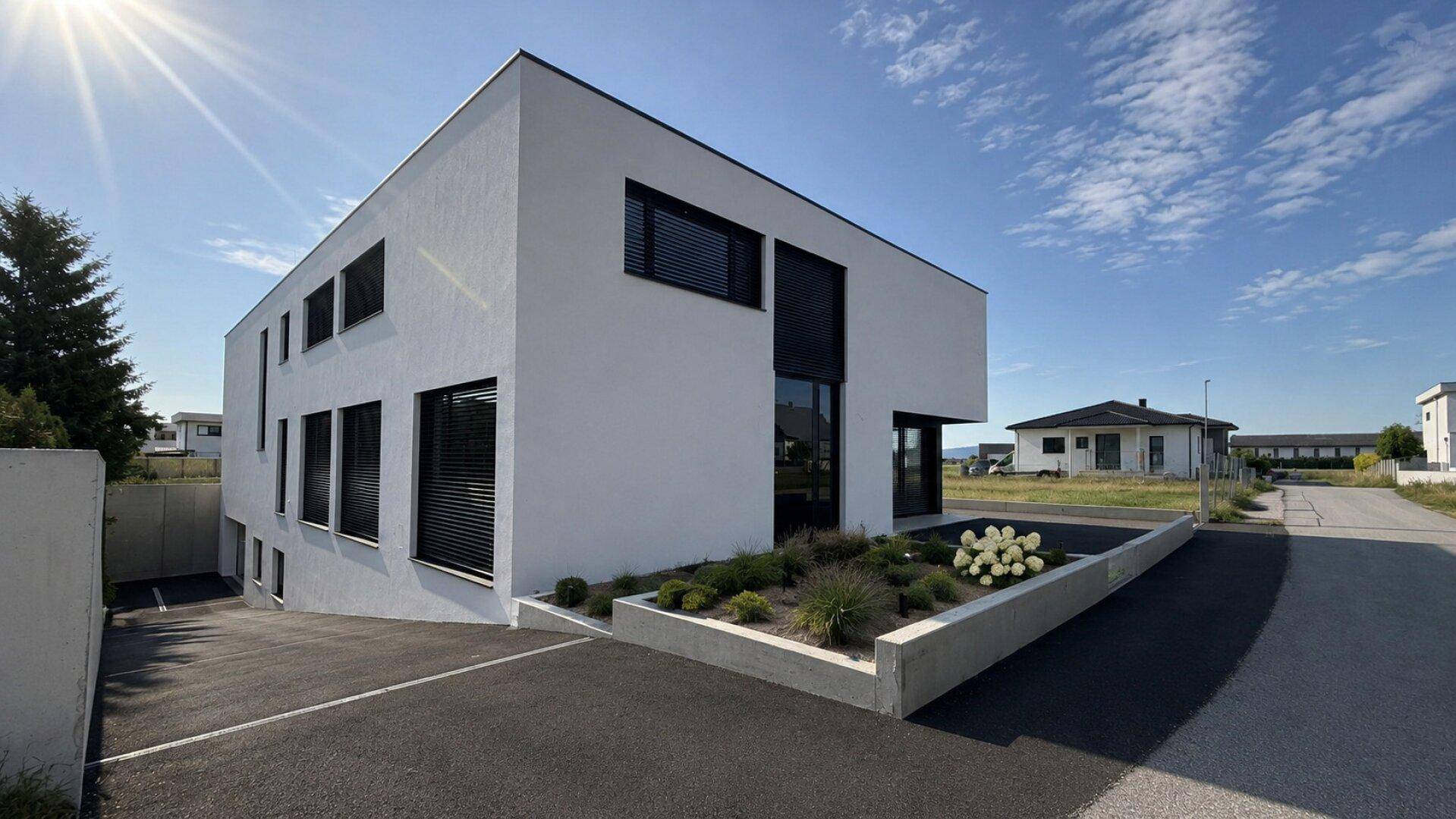 Modernes Einfamilienhaus mit weißer Fassade, großen Fenstern und gepflegter Außenanlage.